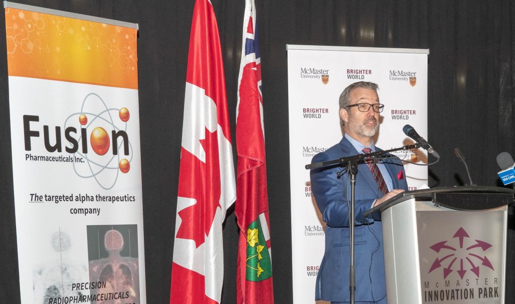 John Valliant speaks at a podium in front of a Fusion banner