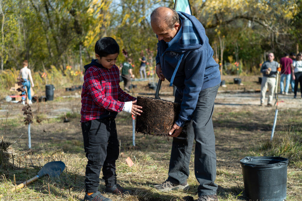 Altaf Arain with his son planting a tree in the McMaster Carbon Sink Forest