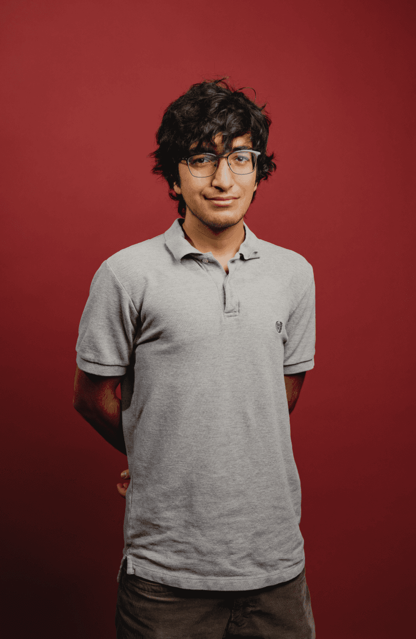 A portrait of Hamza Khattak in front of a red backdrop. Image 1 of 2